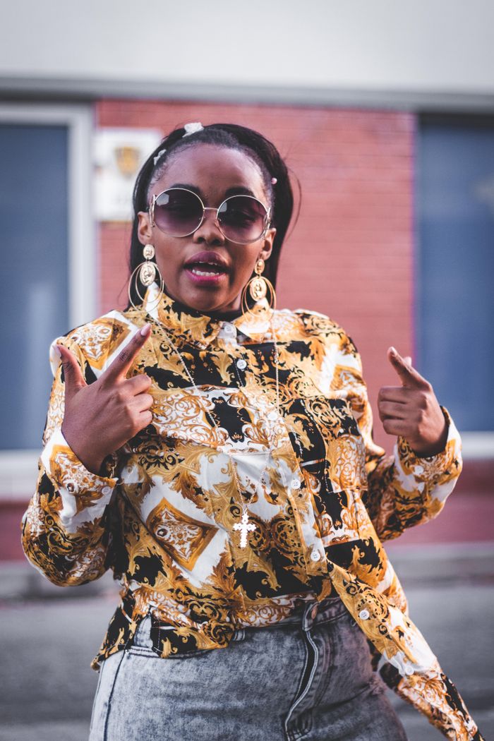Services Confident woman in fashionable attire with sunglasses, posing outdoors.